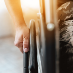 Person with sun behind them and close up on hand on wheelchair